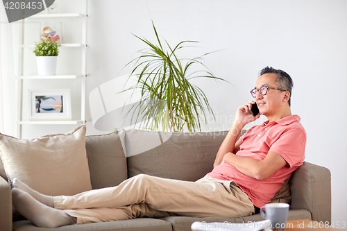 Image of happy man calling on smartphone at home