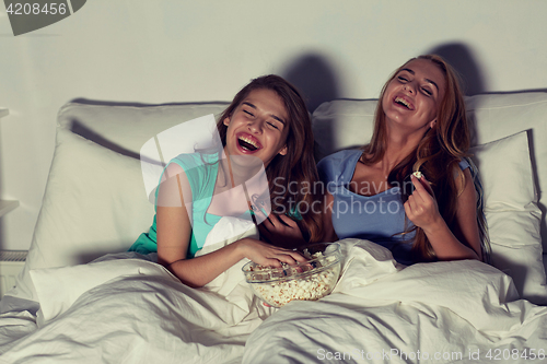 Image of happy friends with popcorn and watching tv at home