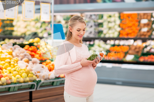 Image of happy pregnant woman with juice at grocery store