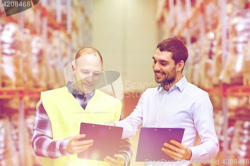 Image of worker and businessmen with clipboard at warehouse