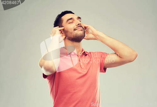 Image of happy man listening to music over gray background