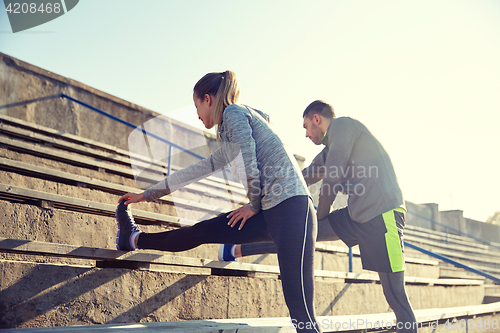 Image of couple stretching leg on stands of stadium