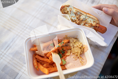 Image of close up of hand with hot dog and sweet potato