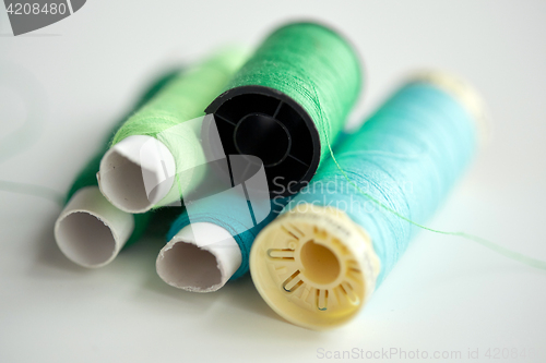 Image of green and blue thread spools on table