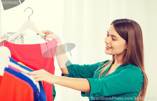 Image of happy woman choosing clothes at home wardrobe