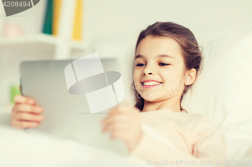 Image of happy girl lying in bed with tablet pc at home