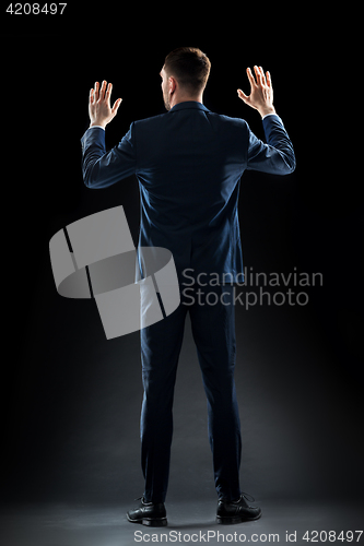 Image of businessman in suit touching something invisible