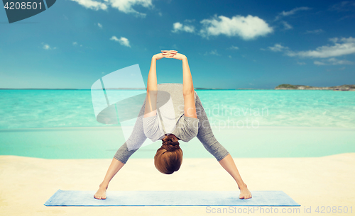 Image of woman making yoga  forward bend on beach 