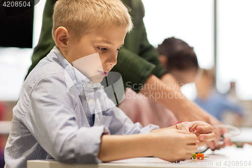 Image of close up of boy building robot at robotics school