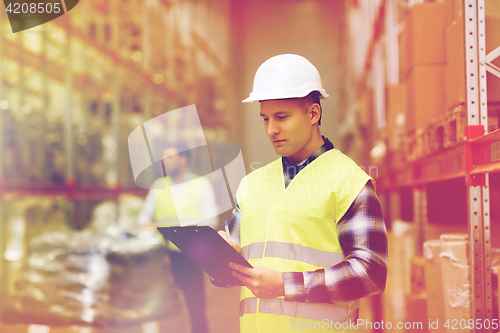 Image of man with clipboard in safety vest at warehouse