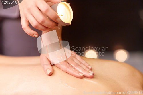 Image of woman doing back massage with hot oil at spa