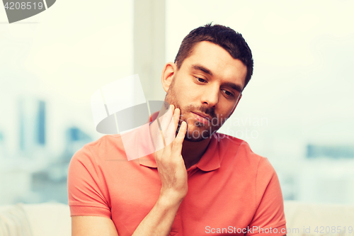 Image of unhappy man suffering toothache at home