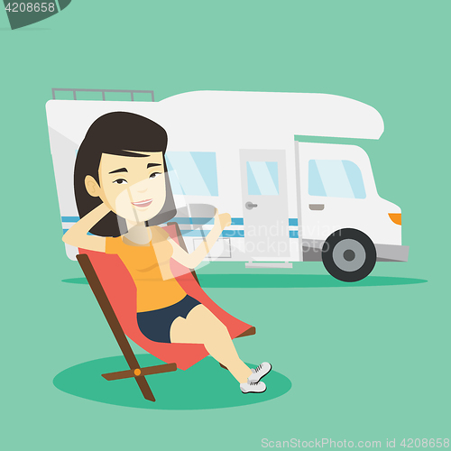 Image of Woman sitting in chair in front of camper van.