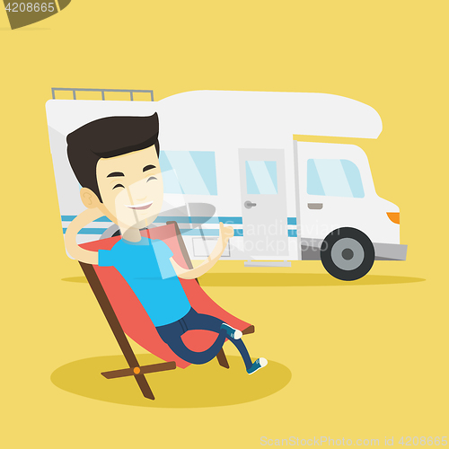 Image of Man sitting in chair in front of camper van.