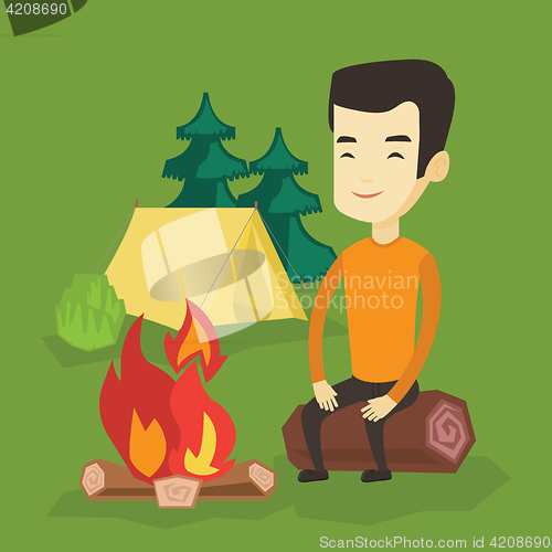 Image of Man sitting on log near campfire in the camping.