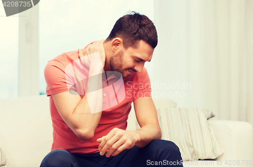 Image of unhappy man suffering from neck pain at home