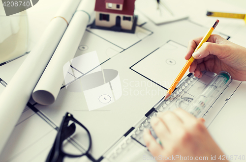 Image of close up of hands with ruler measuring blueprint