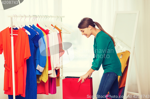 Image of happy woman with shopping bags and clothes at home