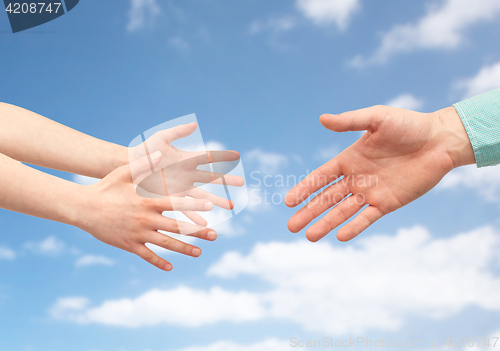 Image of father and child hands over blue sky