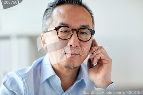 Image of businessman calling on smartphone at office