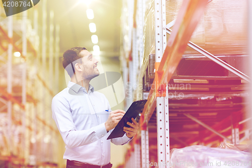 Image of happy businessman with clipboard at warehouse