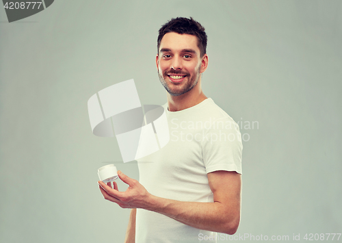 Image of happy young man with cream jar over gray