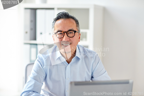 Image of happy businessman in eyeglasses with laptop office