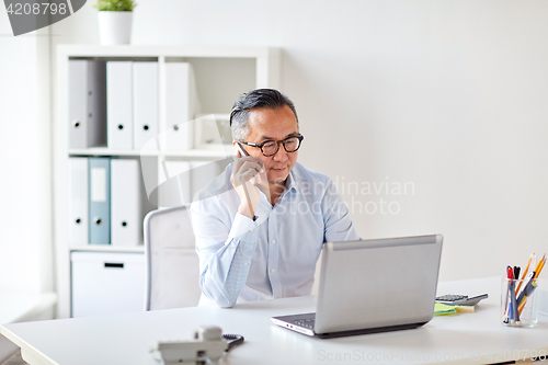 Image of businessman with laptop calling on smartphone