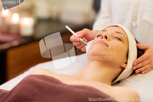 Image of beautician applying facial mask to woman at spa