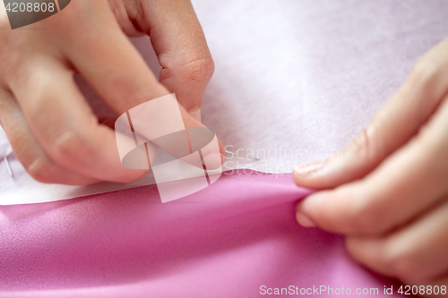 Image of woman with pins stitching paper pattern to fabric