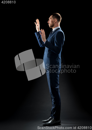 Image of businessman in suit touching something invisible