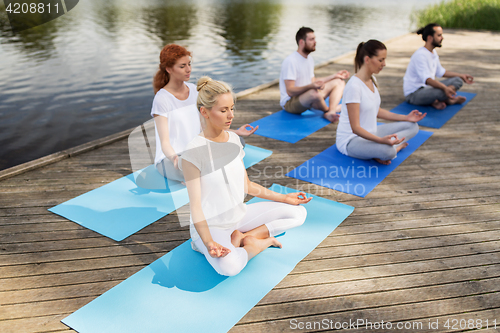 Image of people meditating in yoga lotus pose outdoors