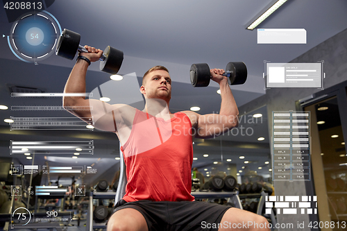 Image of young man with dumbbells flexing muscles in gym