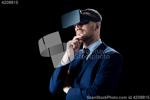 Image of businessman in virtual reality headset over black