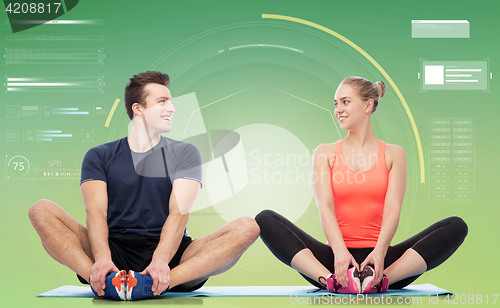 Image of happy sportive man and woman sitting on mats