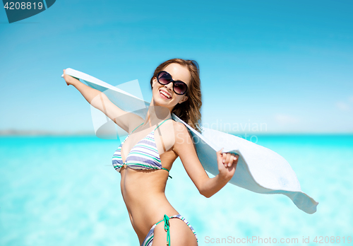 Image of woman in bikini and sunglasses with towel on beach