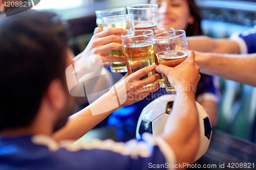 Image of football fans clinking beer glasses at sport bar