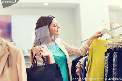 Image of happy young woman choosing clothes in mall