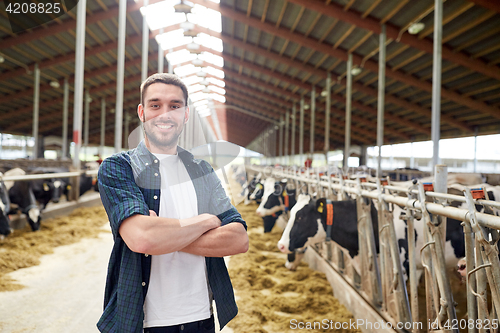 Image of man or farmer with cows in cowshed on dairy farm