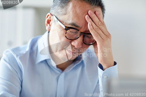 Image of businessman suffering from headache at office