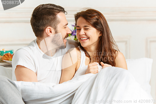 Image of Young adult heterosexual couple lying on bed in bedroom