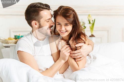 Image of Young adult heterosexual couple lying on bed in bedroom