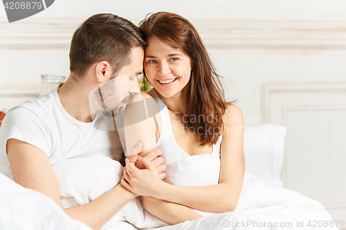 Image of Young adult heterosexual couple lying on bed in bedroom