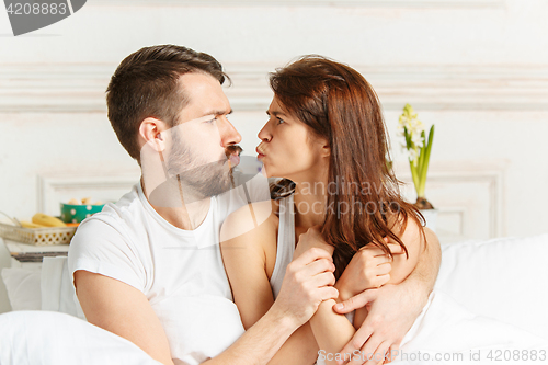 Image of Young adult heterosexual couple lying on bed in bedroom