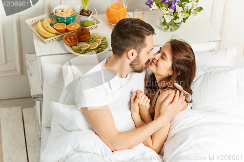 Image of Young adult heterosexual couple lying on bed in bedroom