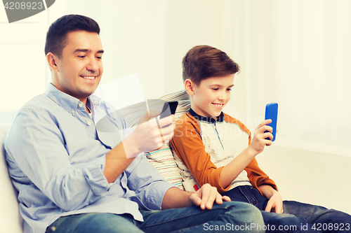 Image of happy father and son with smartphones at home