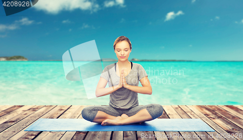 Image of woman making yoga meditation in lotus pose on mat