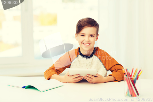 Image of smiling boy with tablet pc and notebook at home