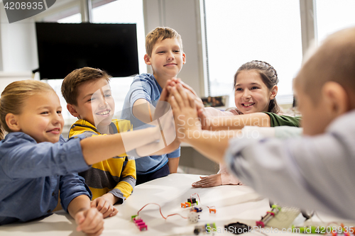 Image of happy children making high five at robotics school