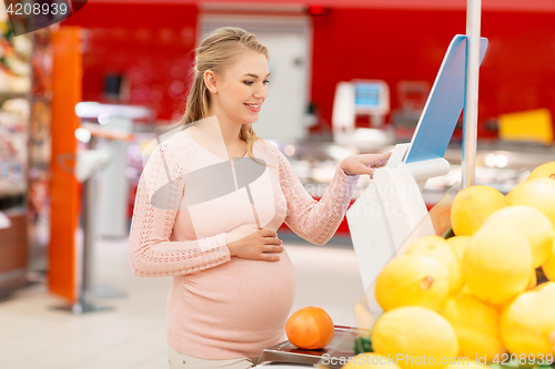 Image of pregnant woman with grapefruit on scale at grocery
